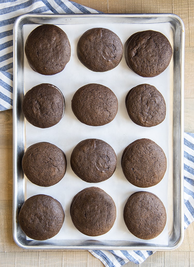 A cookie sheet pan loaded with chocolate cookie sandwiches, arranged in rows of 3x4