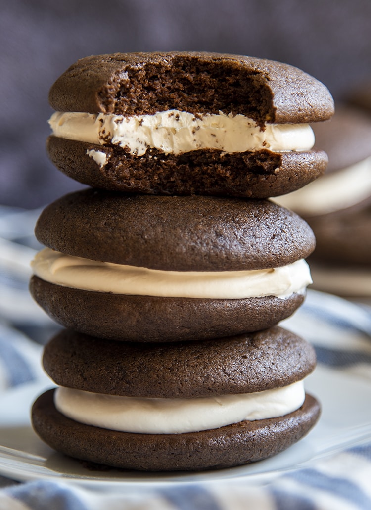 A stack of chocolate whoopie pies with white frosting in the middle. 