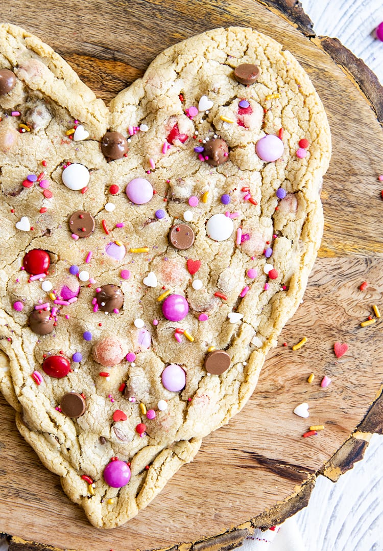 A giant heart shaped cookie on a wooden board.