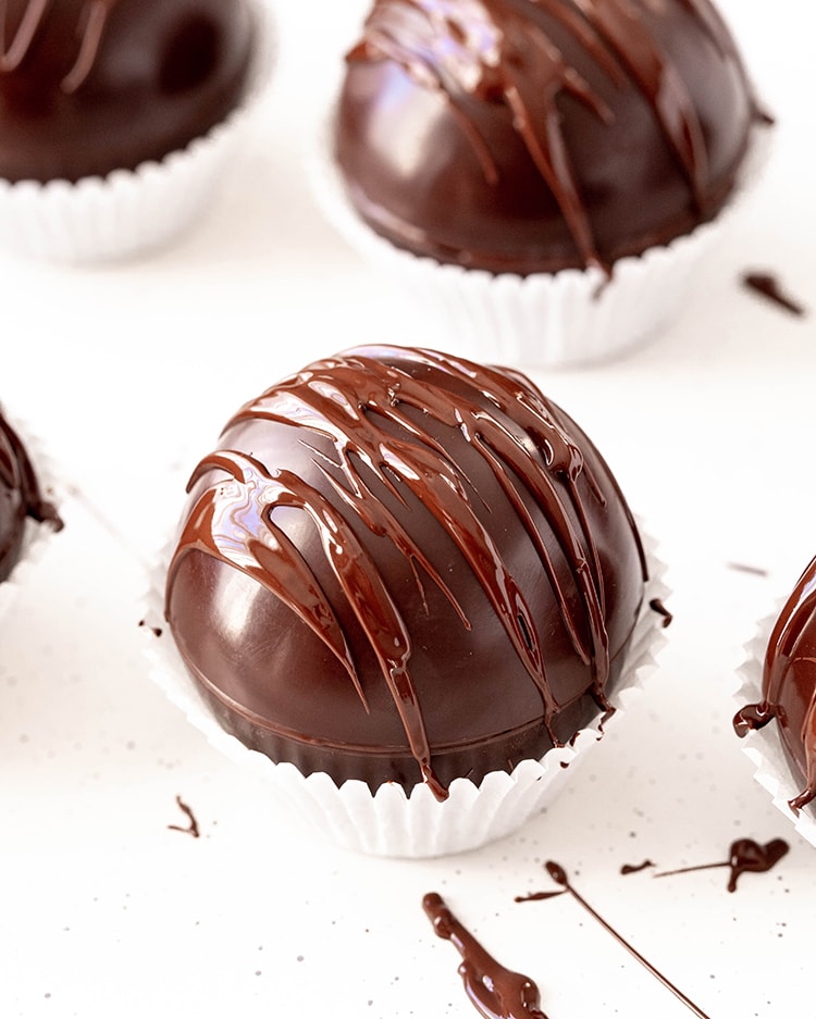 A hot chocolate bomb with melted chocolate drizzled over the top.