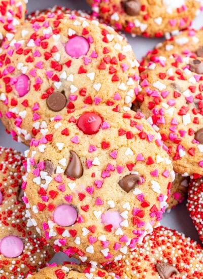 A pile of Valentine M&M cookies coated in red, white, and pink sprinkles.