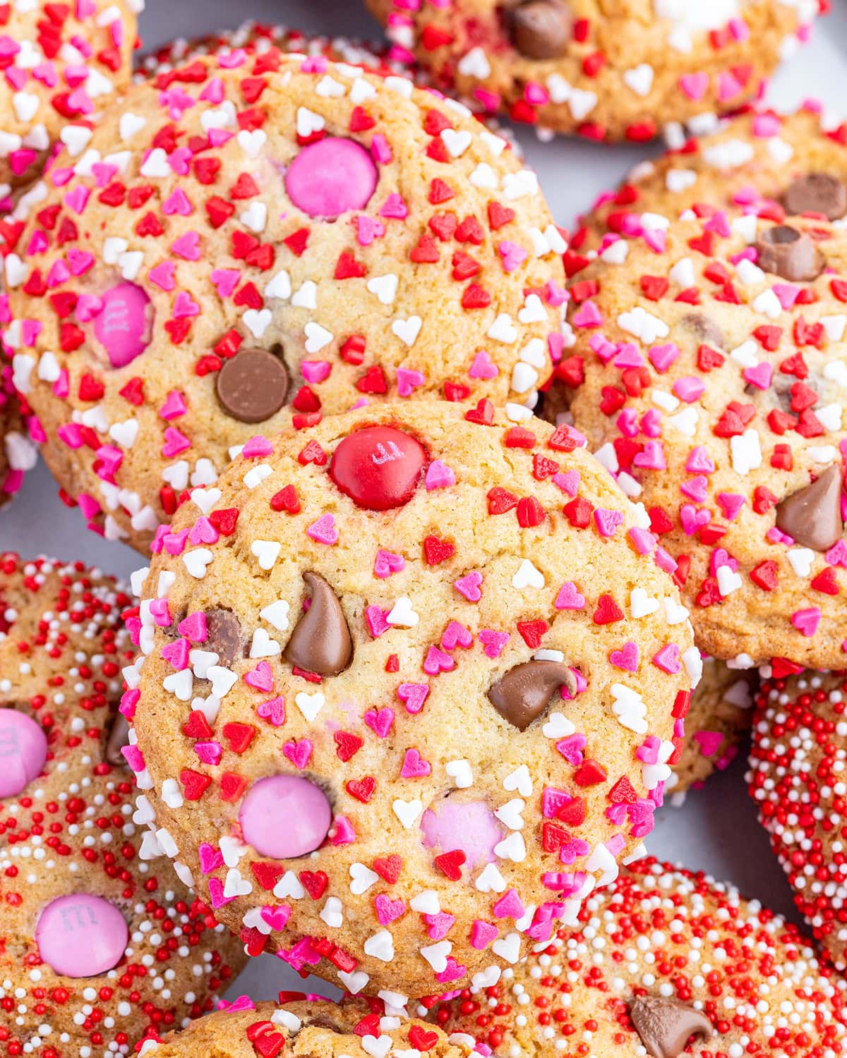 A pile of Valentine M&M cookies coated in red, white, and pink sprinkles.