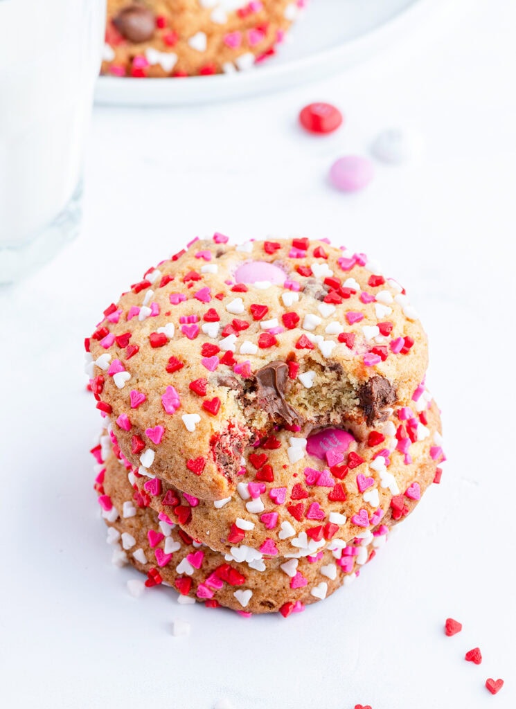 A stack of three Valentine M&M cookies, the top has a bite out of it.