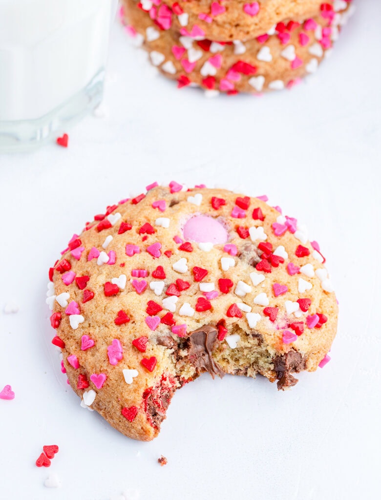 A Valentine Sprinkle M&M cookie with a bite out of it.