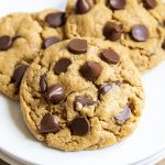 A close up on a peanut butter chocolate chip cookie on a plate, with two cookies behind it.