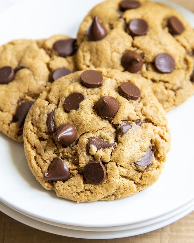 A close up on a peanut butter chocolate chip cookie on a plate, with two cookies behind it.