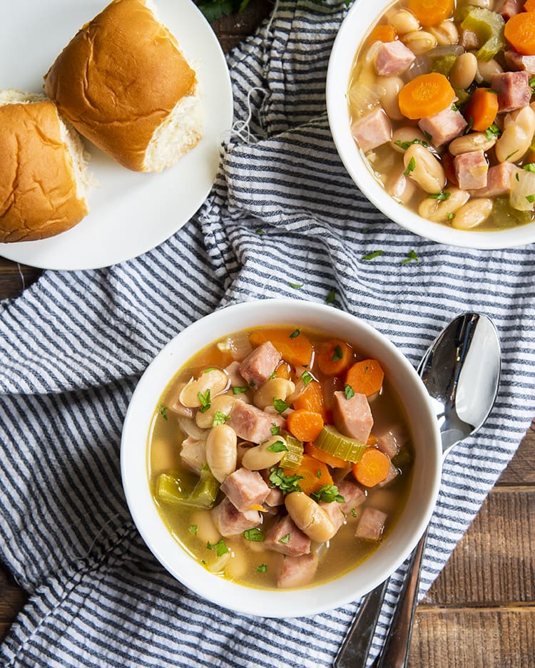Bowls of soup with white beans, cubed ham, and carrots.