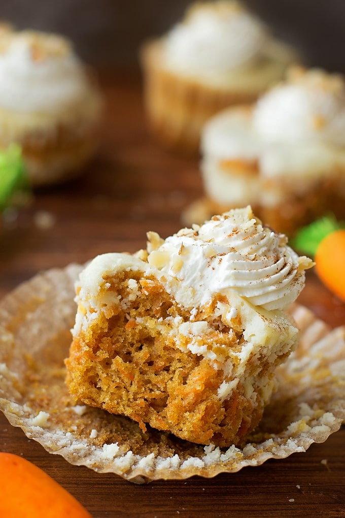 A carrot cake cupcake with a swirl of cheesecake on top, and topped with a swirl of whipped cream.