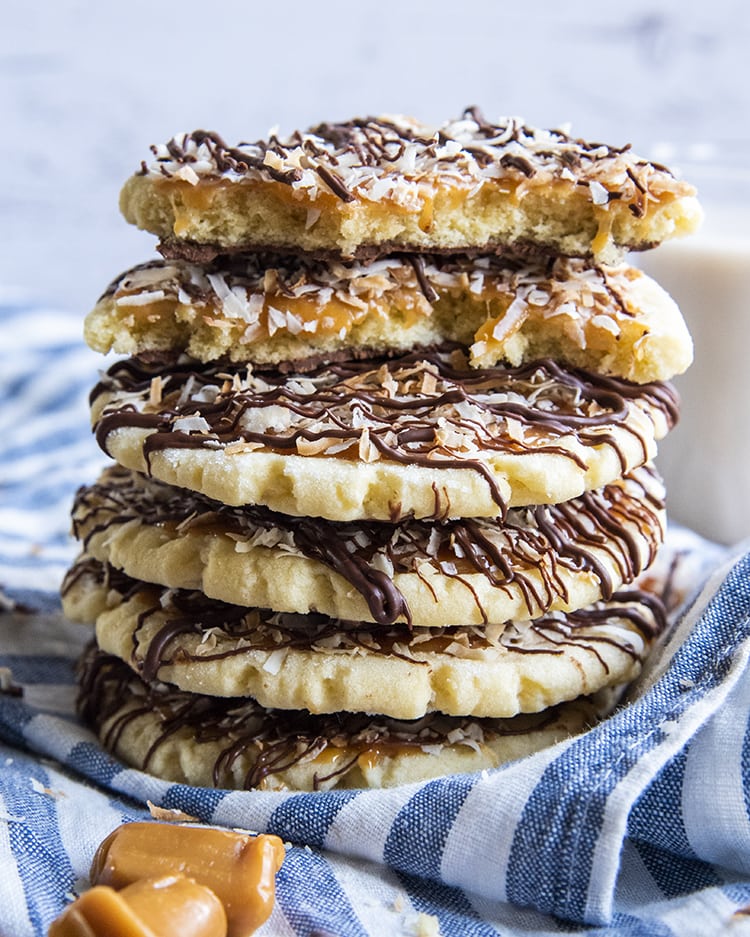 A stack of sugar cookies topped with caramel, coconut, and chocolate drizzles.