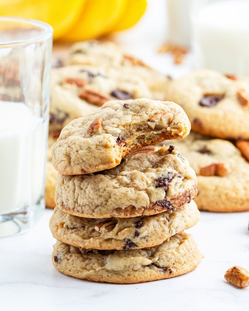 A stack of banana and chocolate chip cookies, and the top cookie has a bite out of it. 