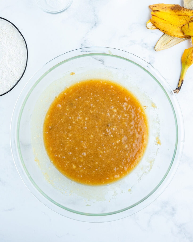 A bowl of mashed banana, butter, and sugar mixed together.
