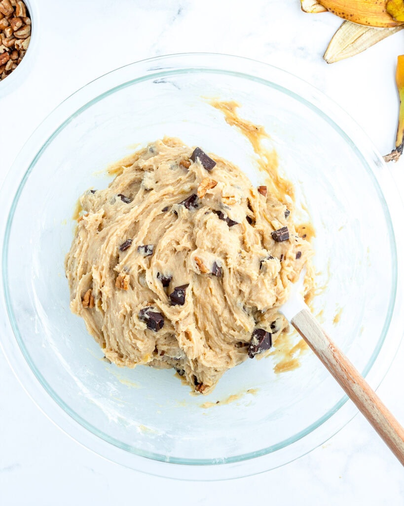 A bowl of cookie dough full of chocolate chunks and pecans.