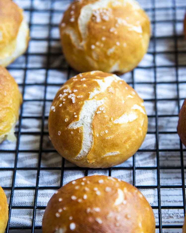 Soft pretzel balls on a cooking rack, they are a nice golden brown color with a couple cracks, and sprinkled with coarse salt on top.