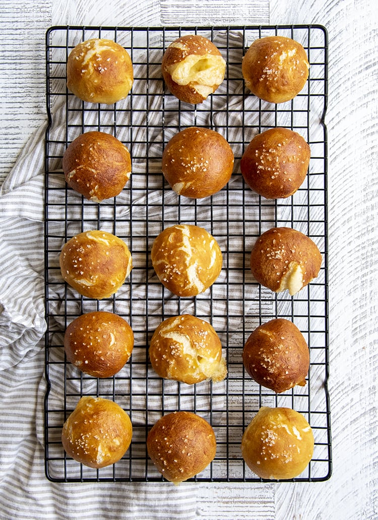 Soft pretzel balls on a cooking rack, they are a nice golden brown color with a couple cracks, and sprinkled with coarse salt on top.