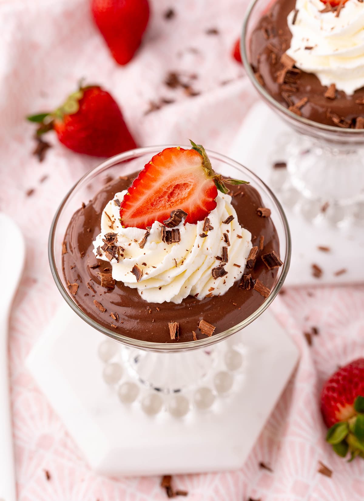 Chocolate pudding in a glass jar topped with whipped cream and a strawberry.