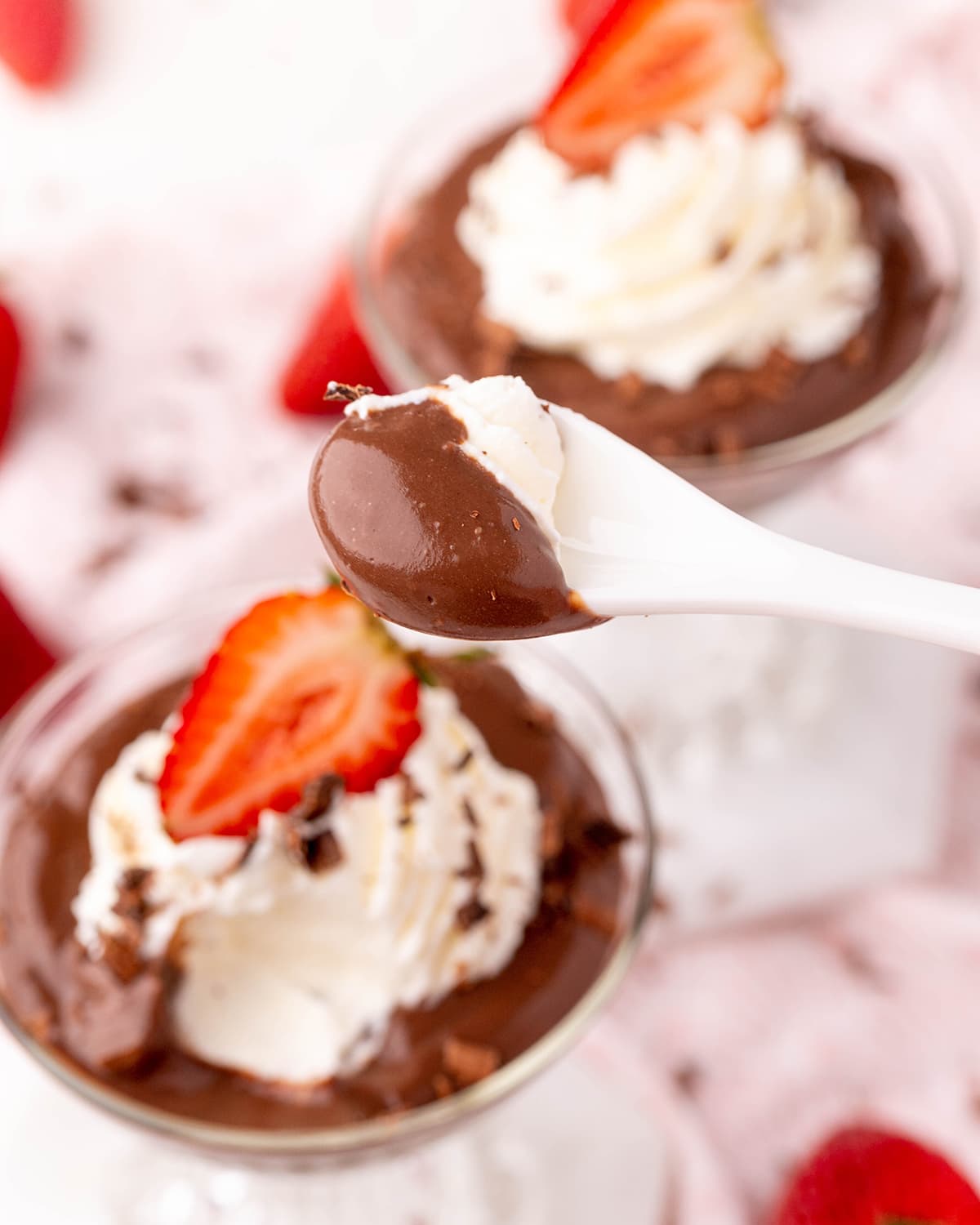 A spoonful of chocolate pudding above a bowl of pudding.