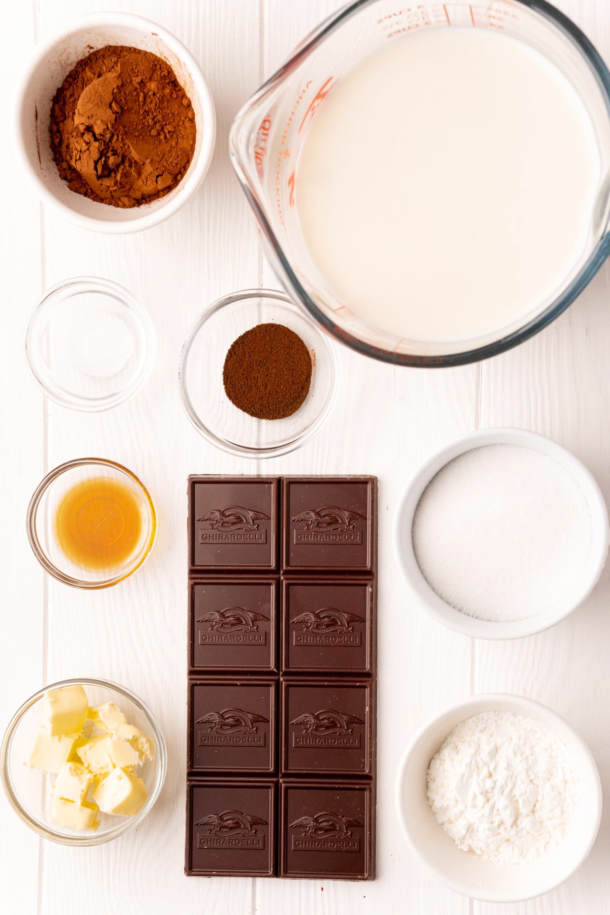 The ingredients needed to make chocolate pudding, cocoa powder, milk, sugar, vanilla, butter, cornstarch, espresso powder, and salt.