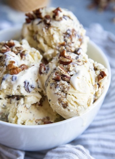 A close up of a bowl of butter pecan ice cream topped with sprinkles of chopped pecans.