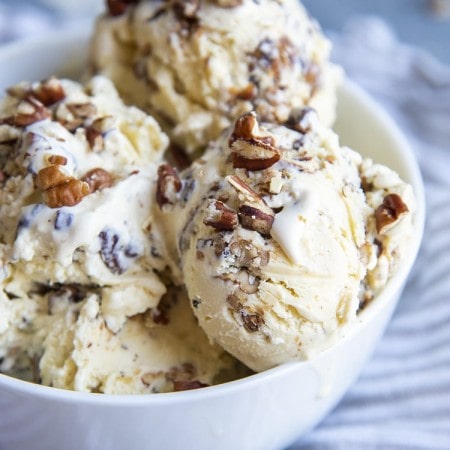 A close up of a bowl of butter pecan ice cream topped with sprinkles of chopped pecans.