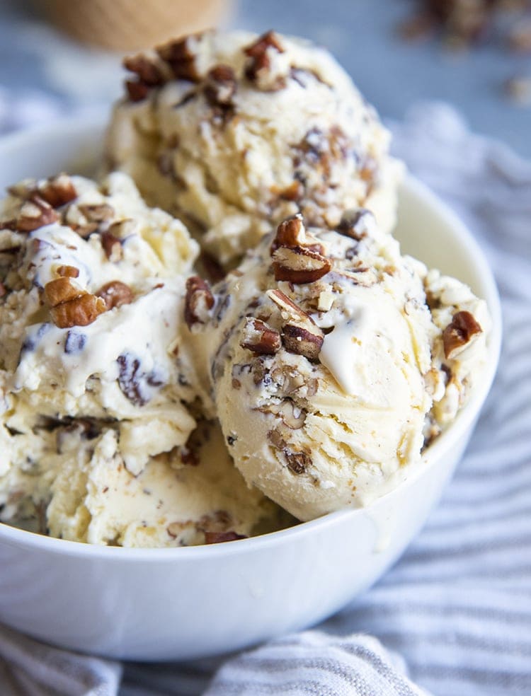 A close up of a bowl of butter pecan ice cream topped with sprinkles of chopped pecans.
