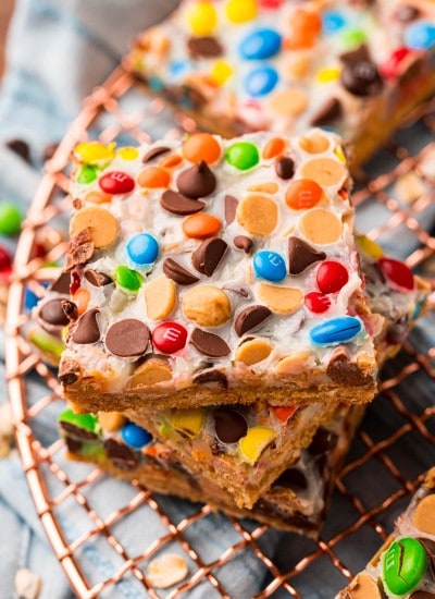 A stack of magic bars with m&ms and chocolate chips showing through the white sweetened condensed milk on top.