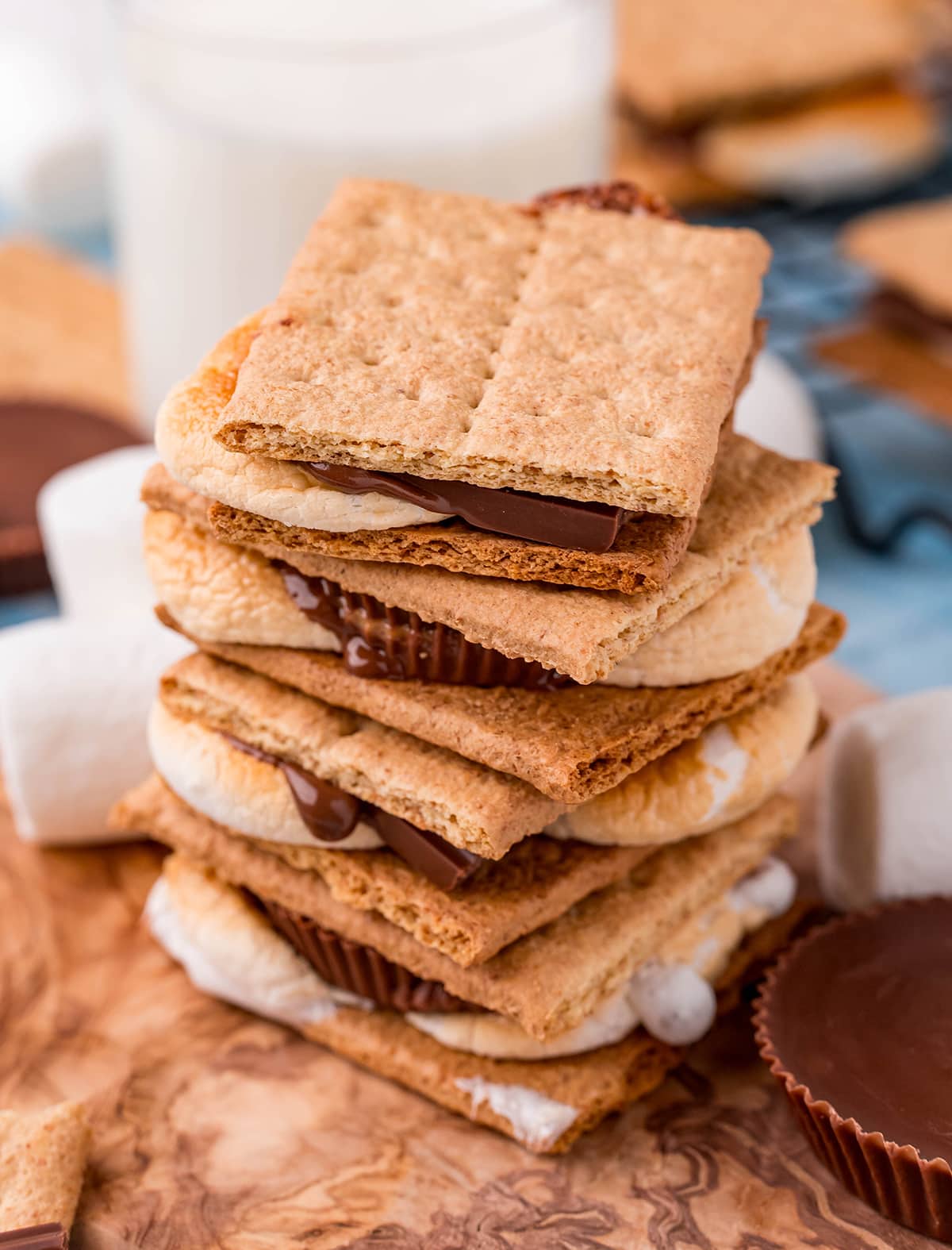 A stack of 4 s'mores on top of each other on a wooden board.