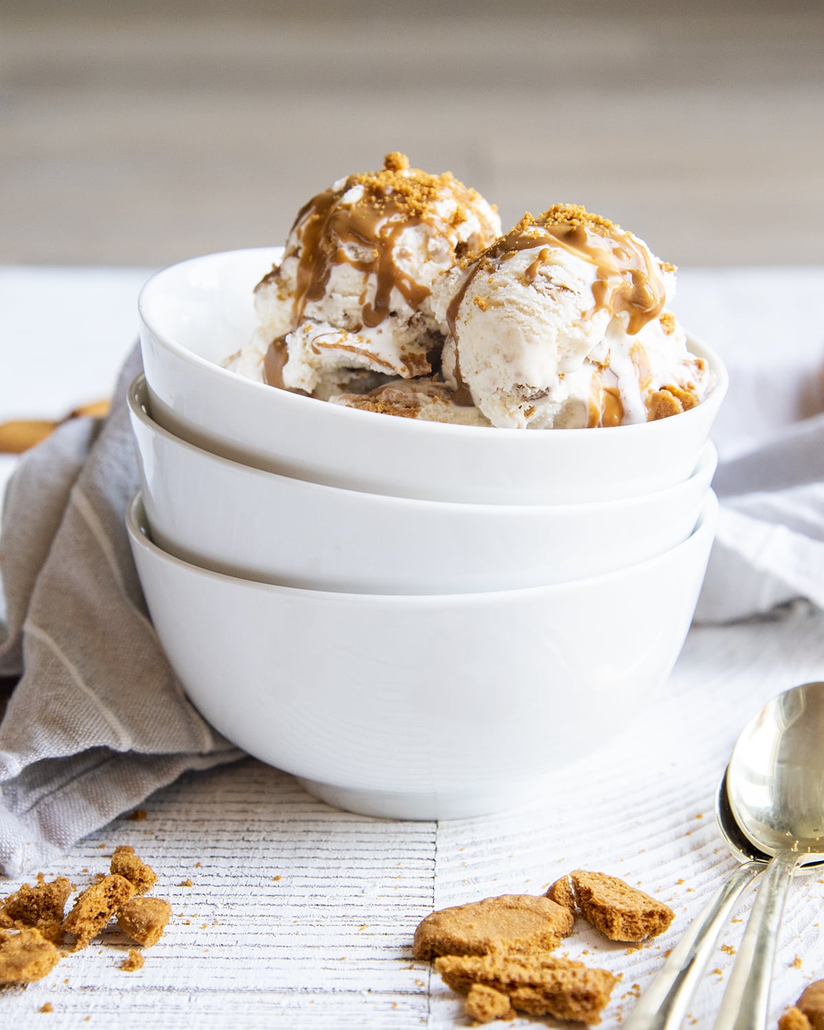 A stack of three white bowls, and the top bowl has Biscoff ice cream in it, topped with cookie butter.