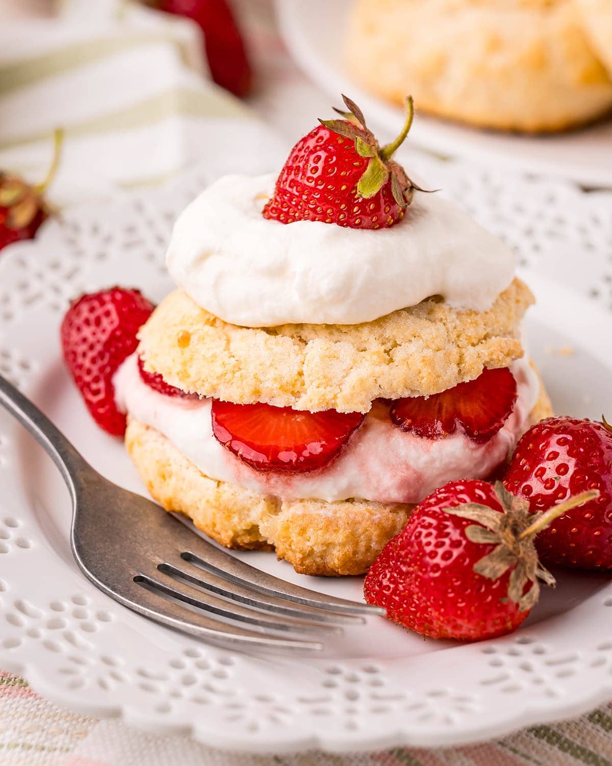 Strawberry shortcakes on a plate with layers of whipped cream and strawberries.