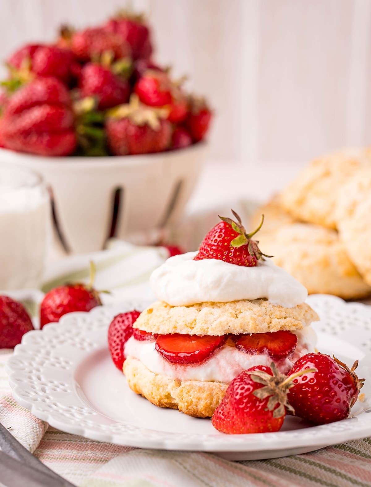 A strawberry shortcake biscuit with strawberries on a plate.