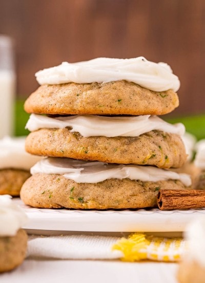 A stack of three zucchini cookies topped with cream cheese frosting.