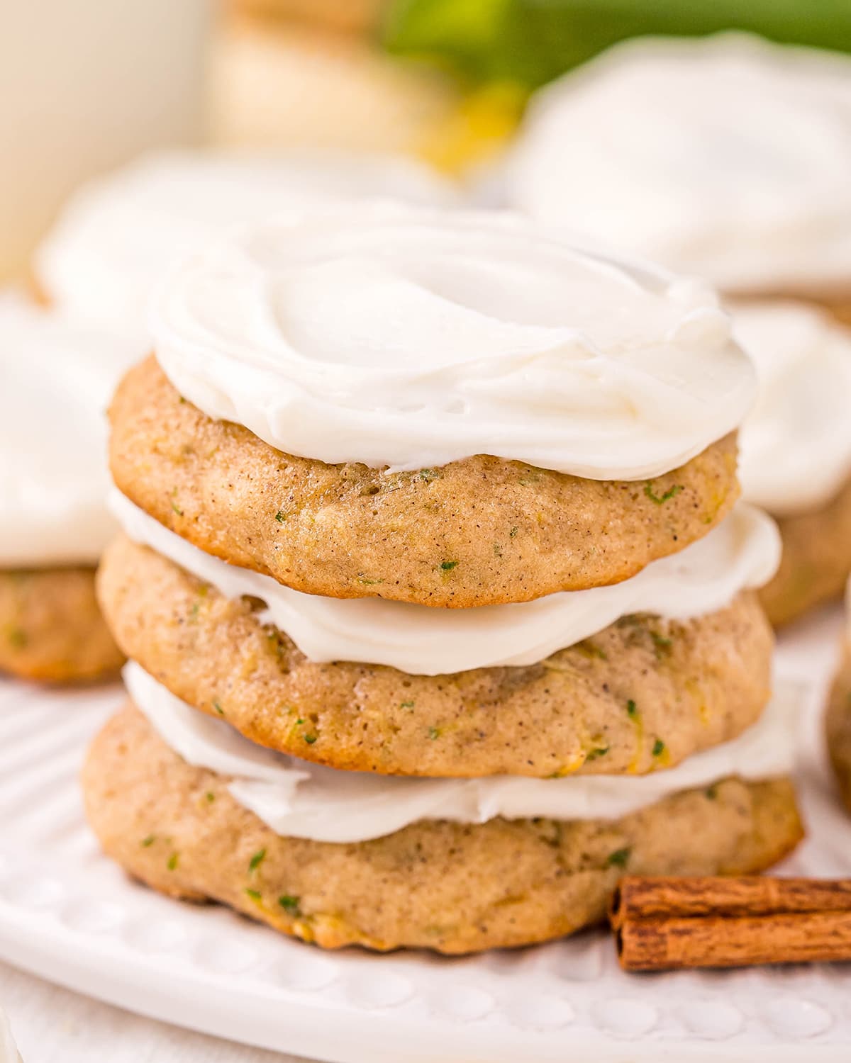 A stack of three zucchini cookies topped with cream cheese frosting.