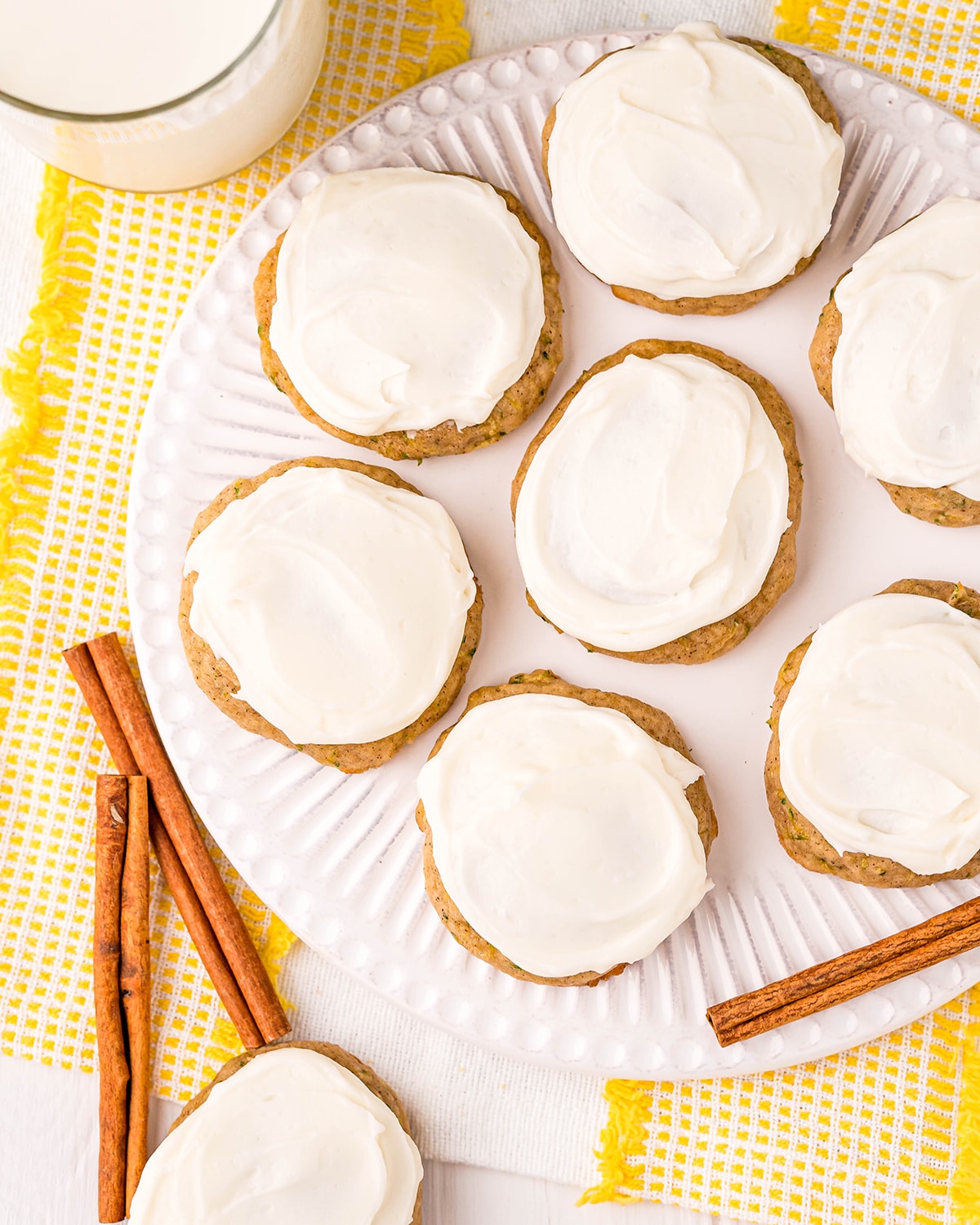 An overhead shot of a plate of cookies, topped with a white cream cheese frosting.