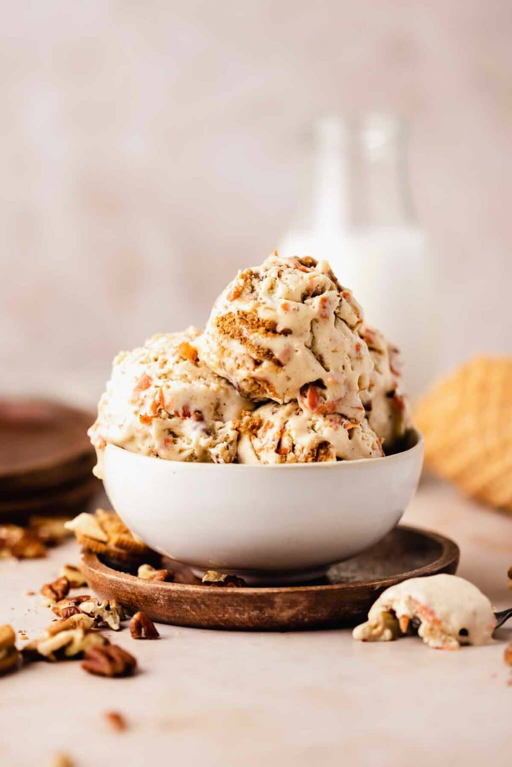 A bowl of ice cream piled high with scoops of ice cream with grated carrots and Oreo cookie pieces in them.