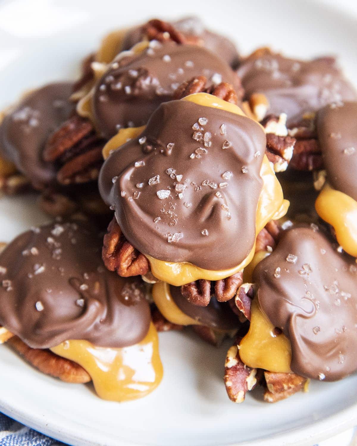 A pile of chocolate turtle candies sprinkled with sea salt on a plate.