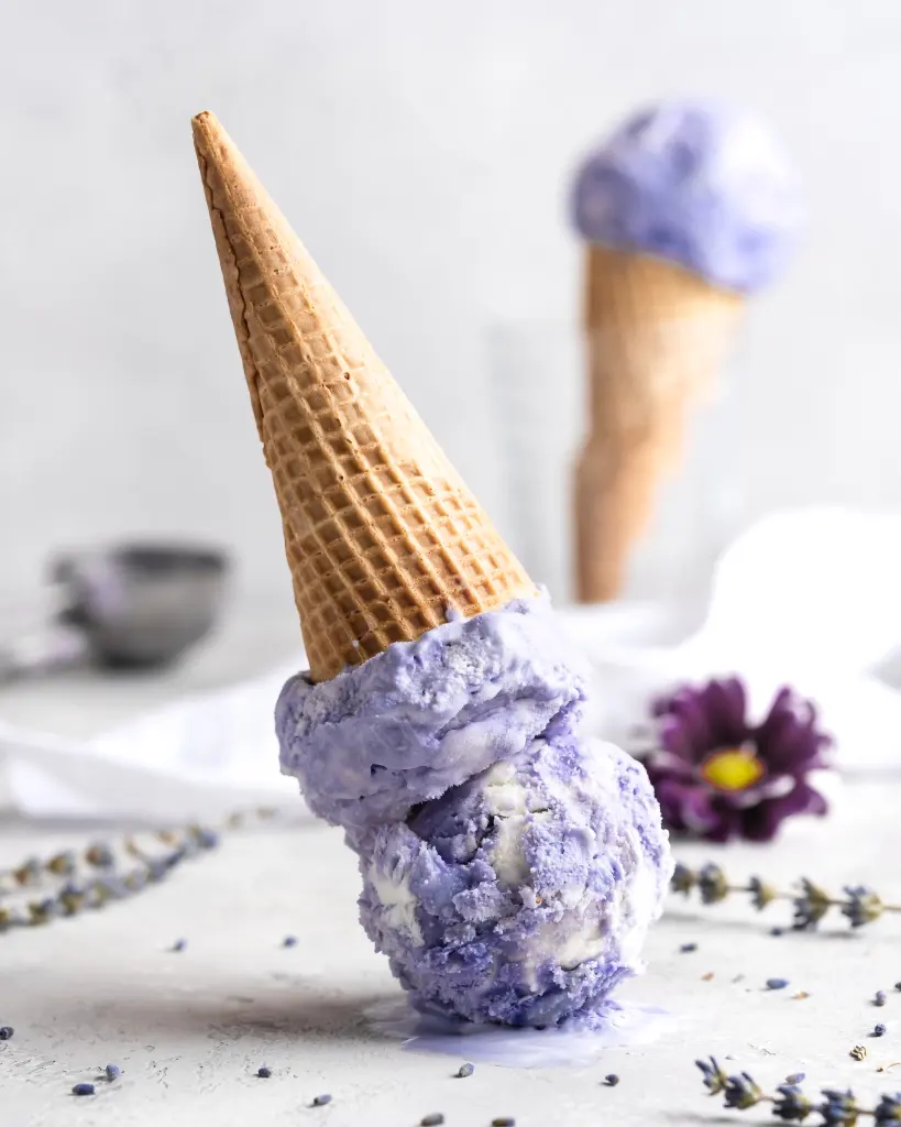 An upside down ice cream cone with two scoops of purple lavender ice cream.