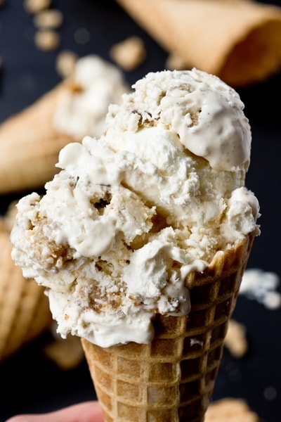 An ice cream cone topped with large scoops of vanilla ice cream and coffee cake crumbs.