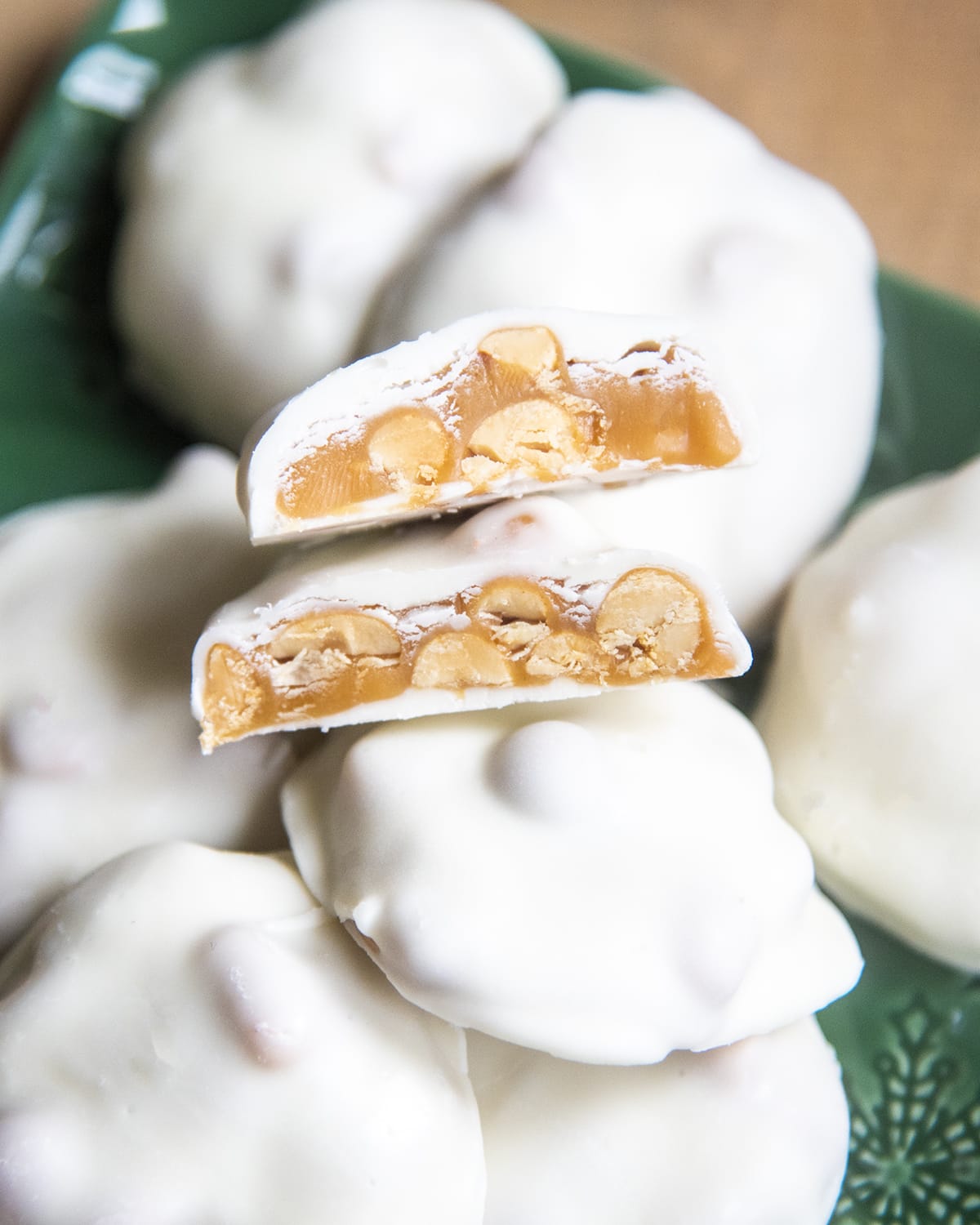 A caramel pecan cluster covered in white chocolate and cut in half showing the middle.