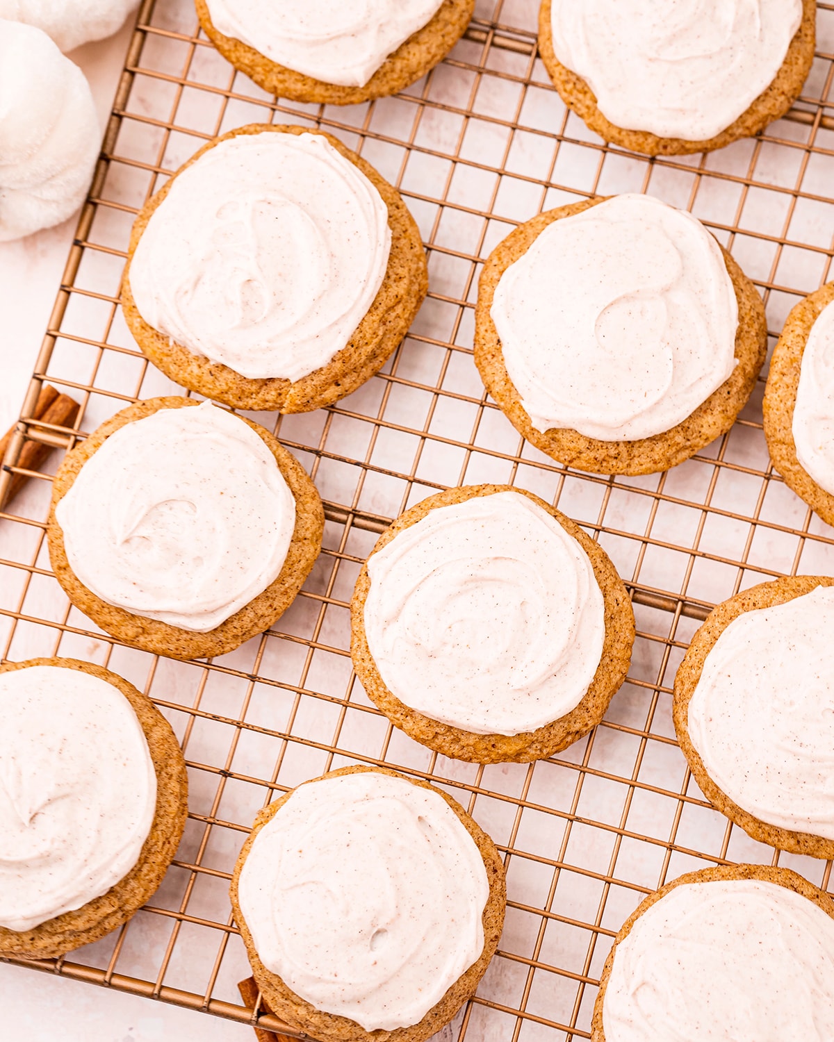 An overhead shot of Pumpkin Cookies with cream cheese frosting on a cooling rack.
