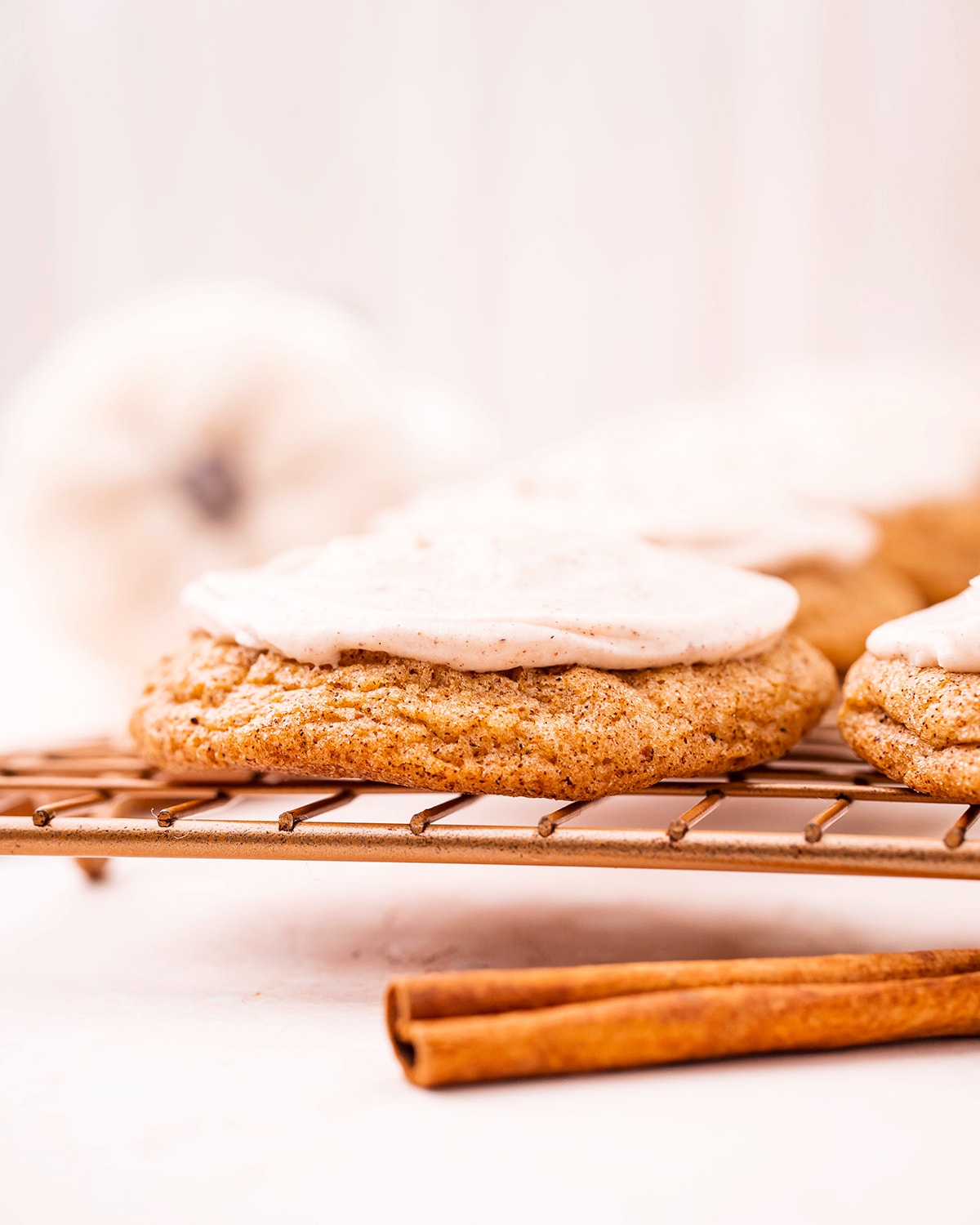 A pumpkin cookie with cream cheese frosting on a cooling rack.