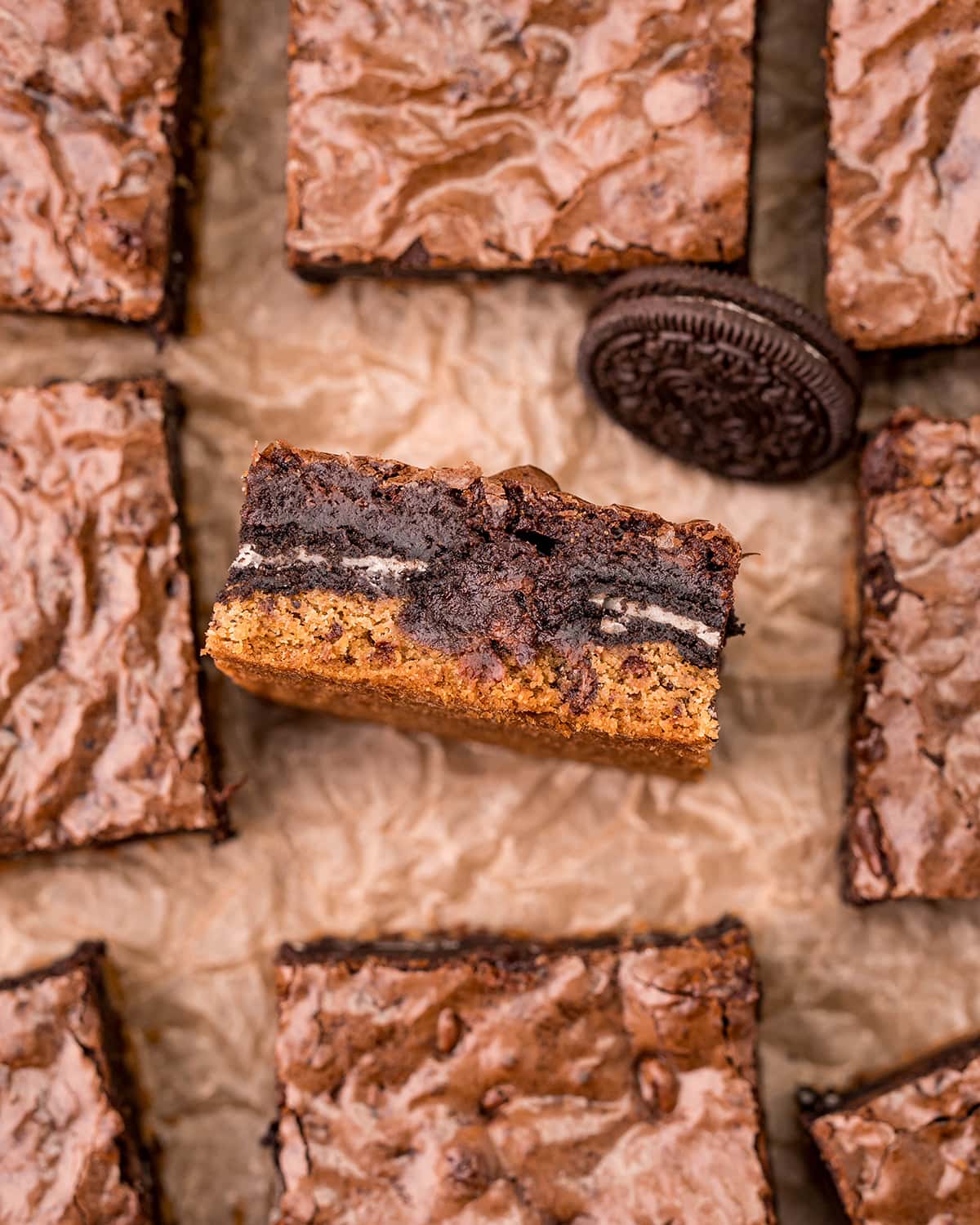 A slutty brownie brookie on its side, with a layer of chocolate chip cookie, Oreos, and brownie.