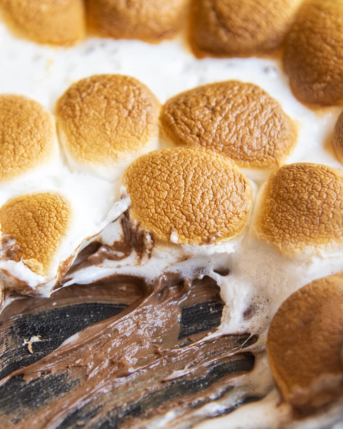 A close up of s'mores dip, showing toasted marshmallows above melted chocolate.