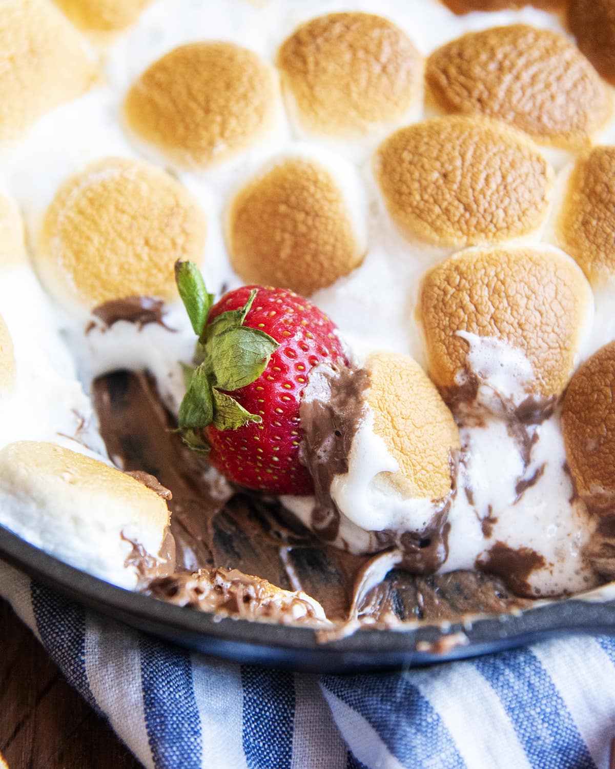 A strawberry in a pan of s'mores dip.