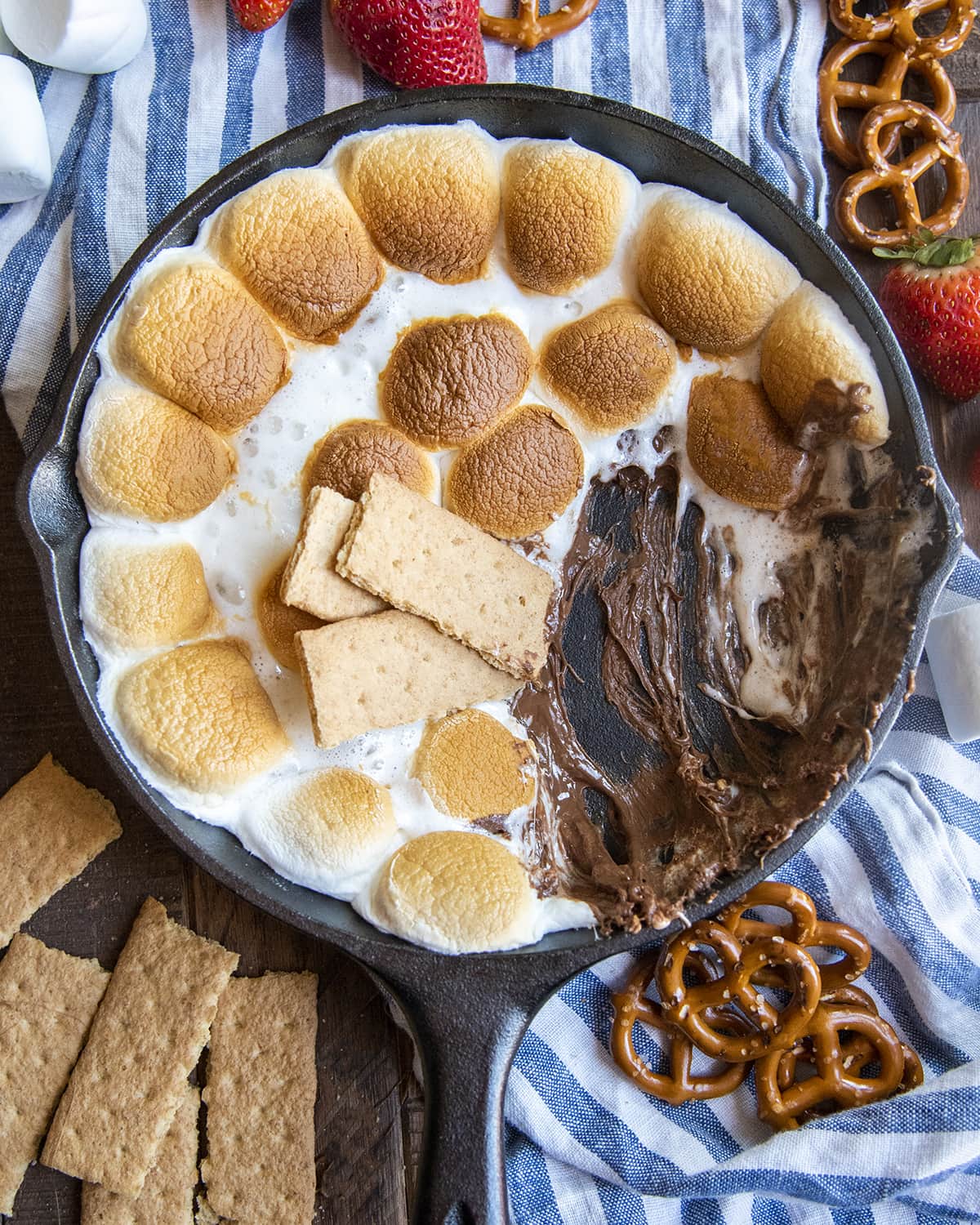 A chocolate and marshmallow s'mores dip in a cast iron pan with some graham crackers in there.