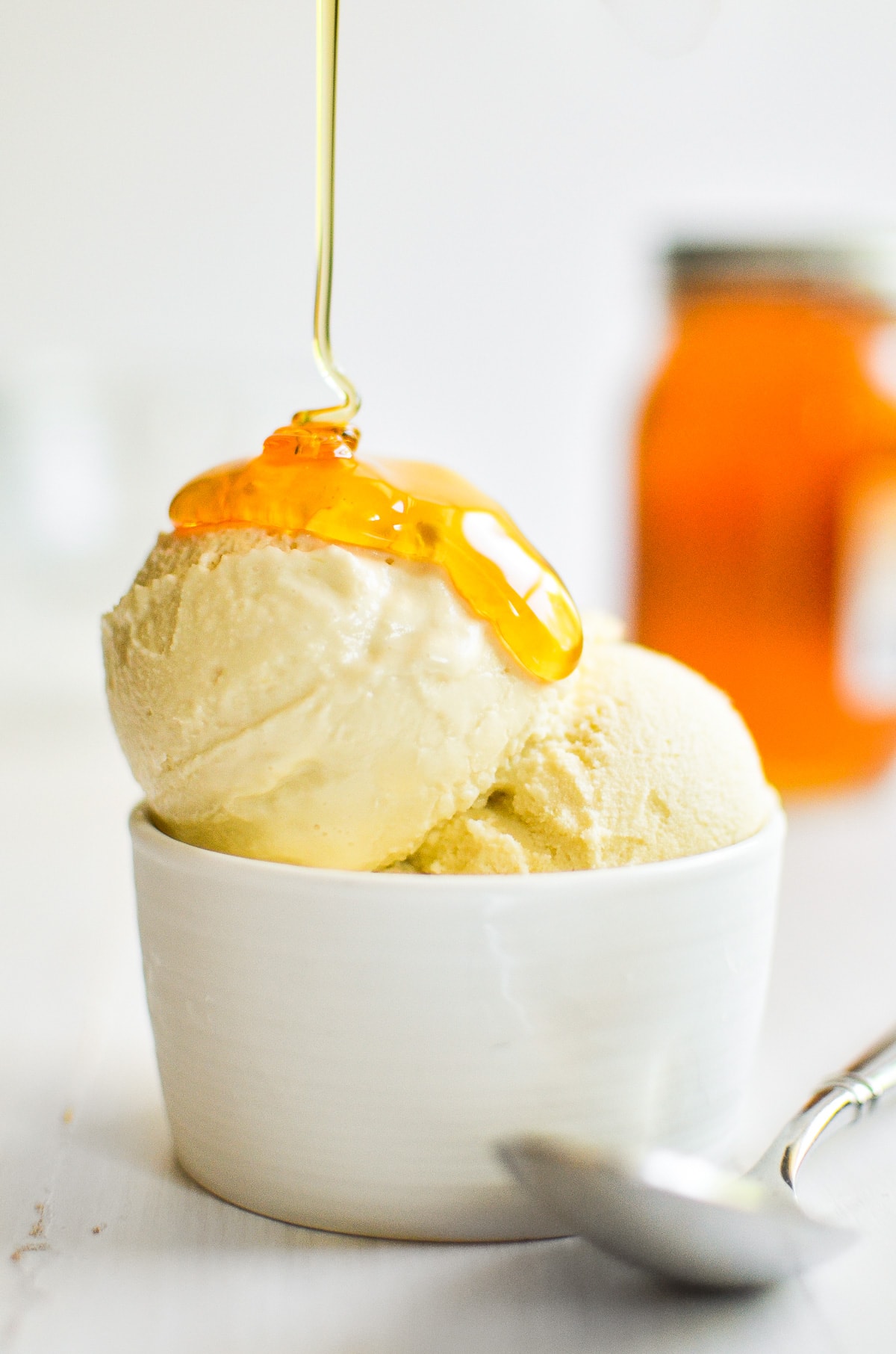 A bowl of honey ice cream with honey drizzled over the top. 