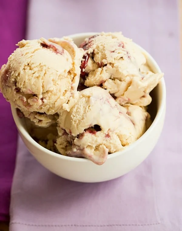 A bowl of peanut butter ice cream with swirls of grape jelly throughout the scoops.