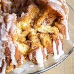 Cinnamon roll monkey bread on a glass plate with a few pieces taken out showing the inside of the bread.
