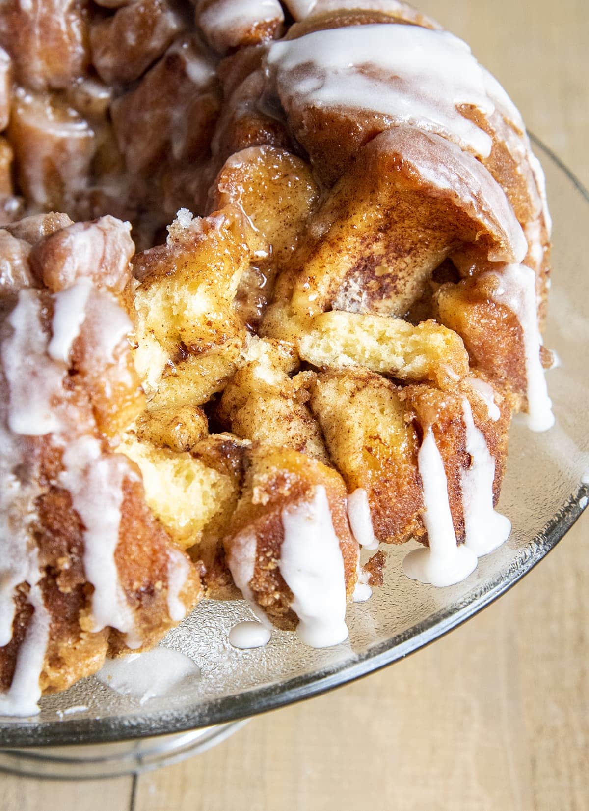 Cinnamon roll monkey bread on a glass plate with a few pieces taken out showing the inside of the bread.