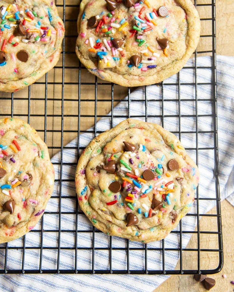 A close up of giant sprinkle and chocolate chip cookies on a cooling rack!