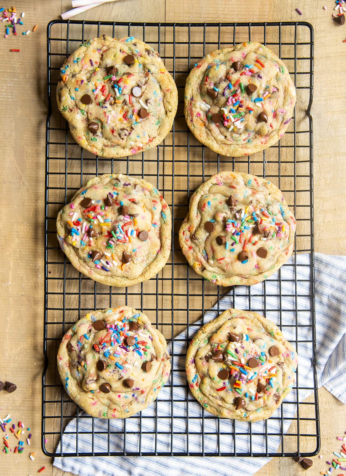 An overhead photo of 6 giant chocolate chip funfetti cookies on a cooling rack.
