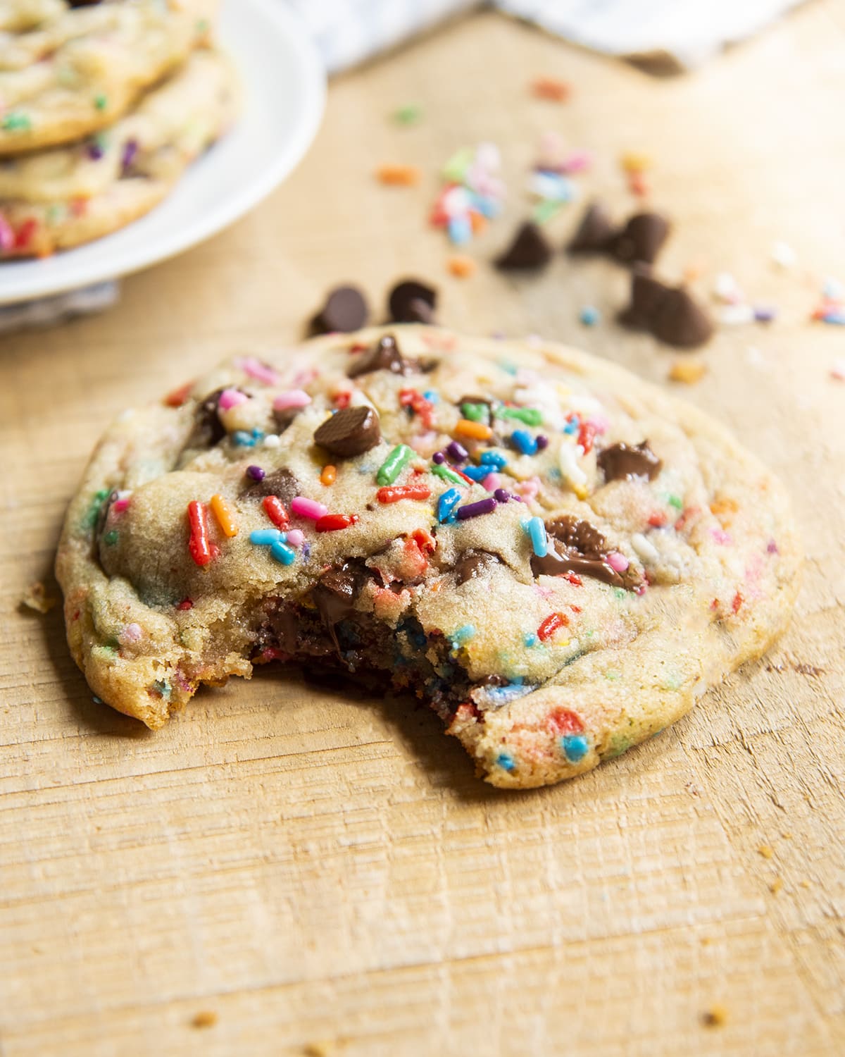 A giant chocolate chip cookie with sprinkles, with a bite taken out of it.